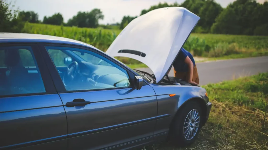 man looking under car hood